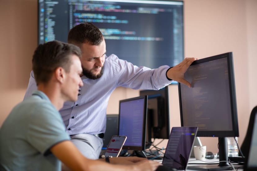 Softwareentwickler arbeiten gemeinsam mit KI-Unterstützung an Code